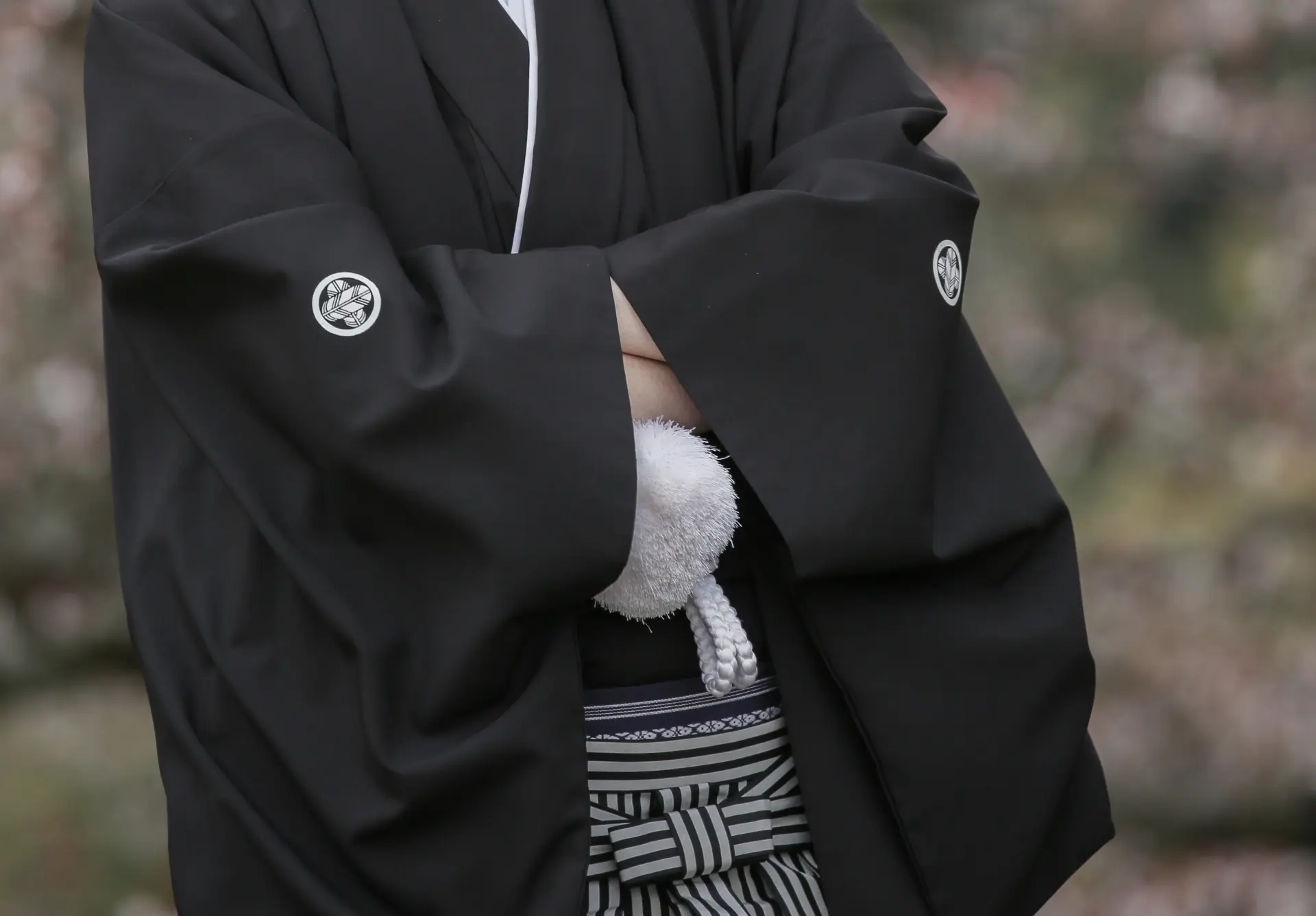 a man in a black kimono is standing with his arms crossed