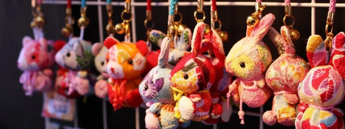 Row of colorful patterned fabric animal charms, including rabbits and bears, each with a bell.