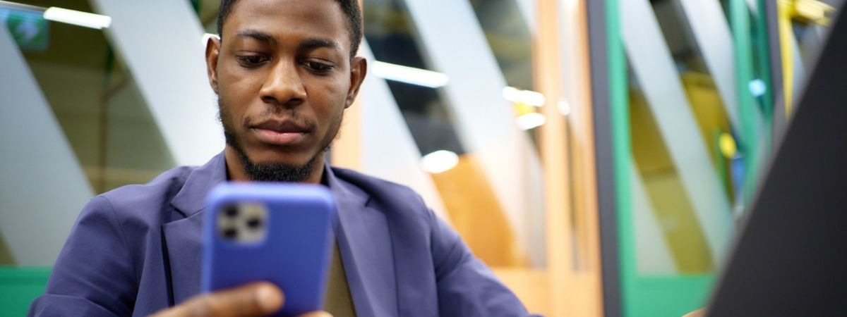 A young Black man looking at his smartphone.