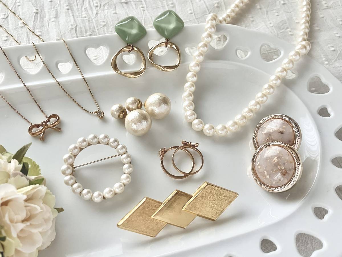 A white tray holds a variety of jewelry, including pearl necklaces, a pearl brooch