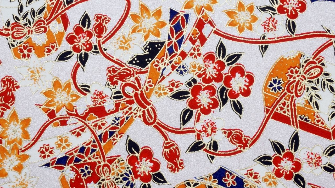 Traditional Japanese fabric pattern with red and orange flowers, fans, and ribbons on a white background, outlined in gold.