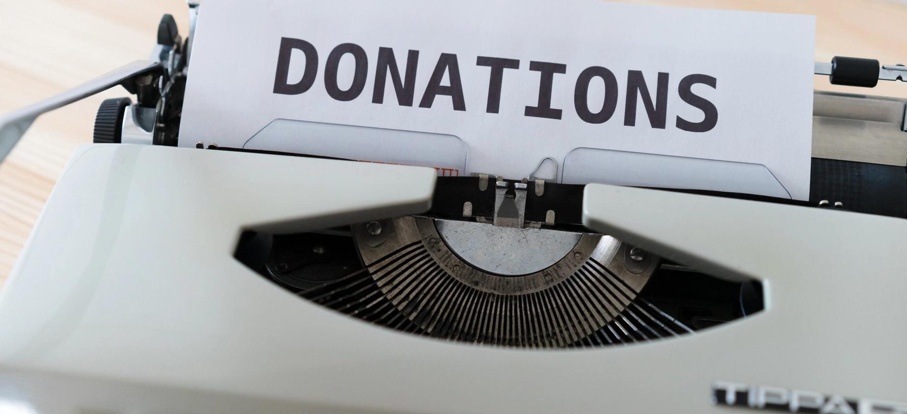 typewriter showing a piece of paper with donations written
