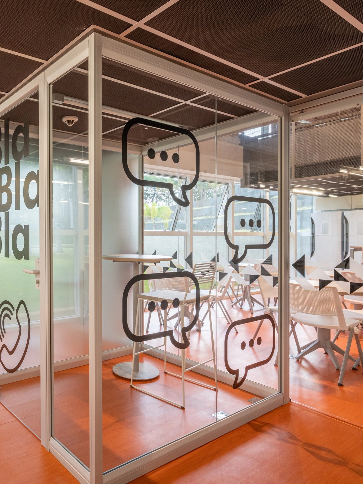 Sala de reunião em vidro com adesivos de balões de diálogo, linha Ackua.