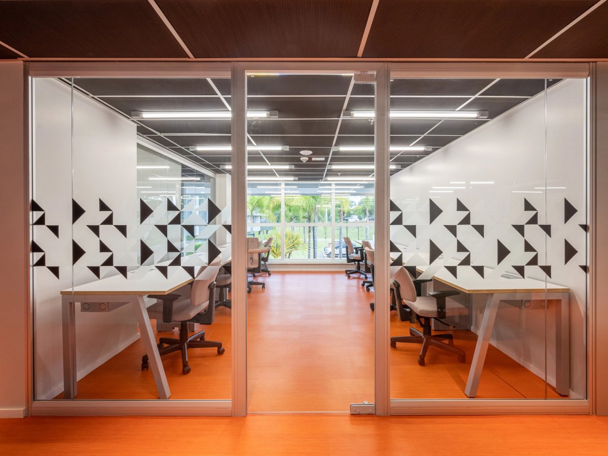 Salas envidraçadas da linha Ackua com adesivos geométricos e piso laranja, foto do catálogo.