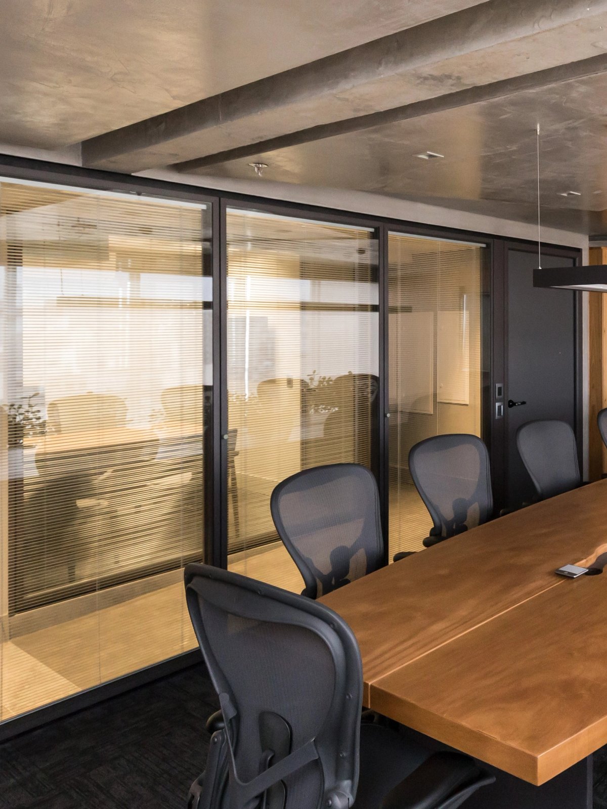 Sala de reunião com mesa em madeira e divisórias Calibra.