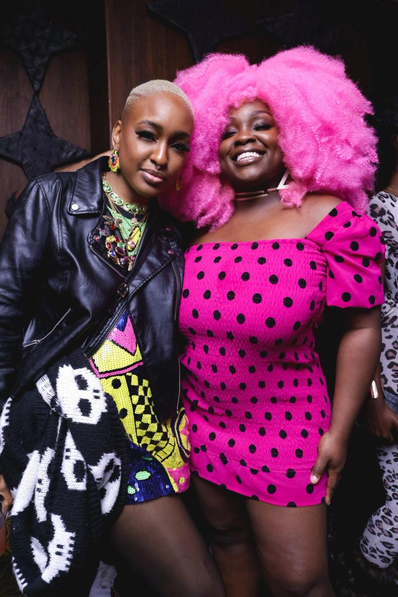 Two guests in bright outfits posing together