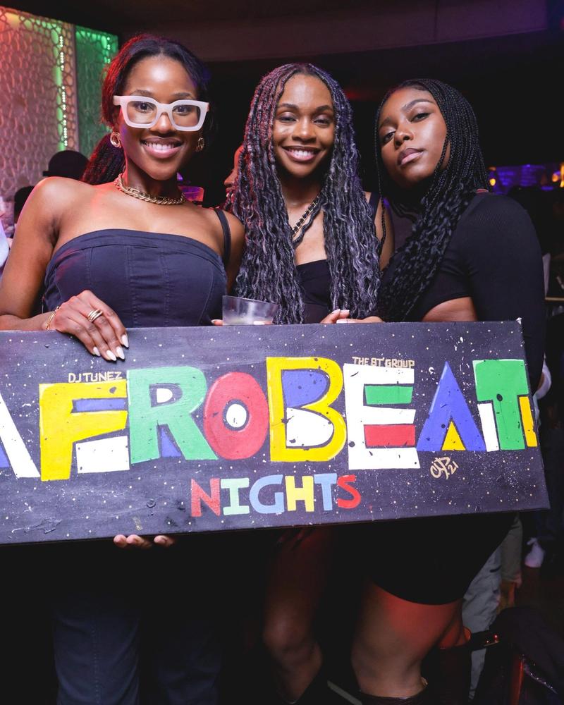 Guests beside the illuminated Afrobeat Nights sign