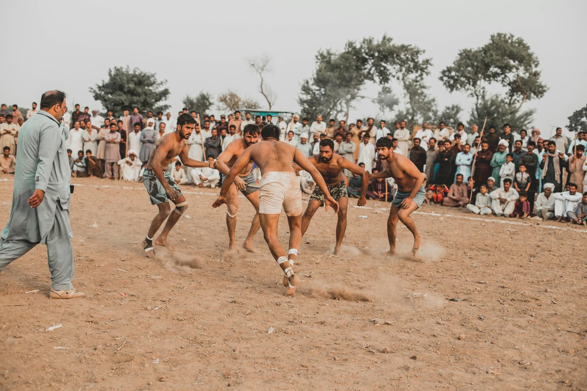 Men engage in a traditional Kabaddi match in Sillanwali, Pakistan with a large crowd watching.