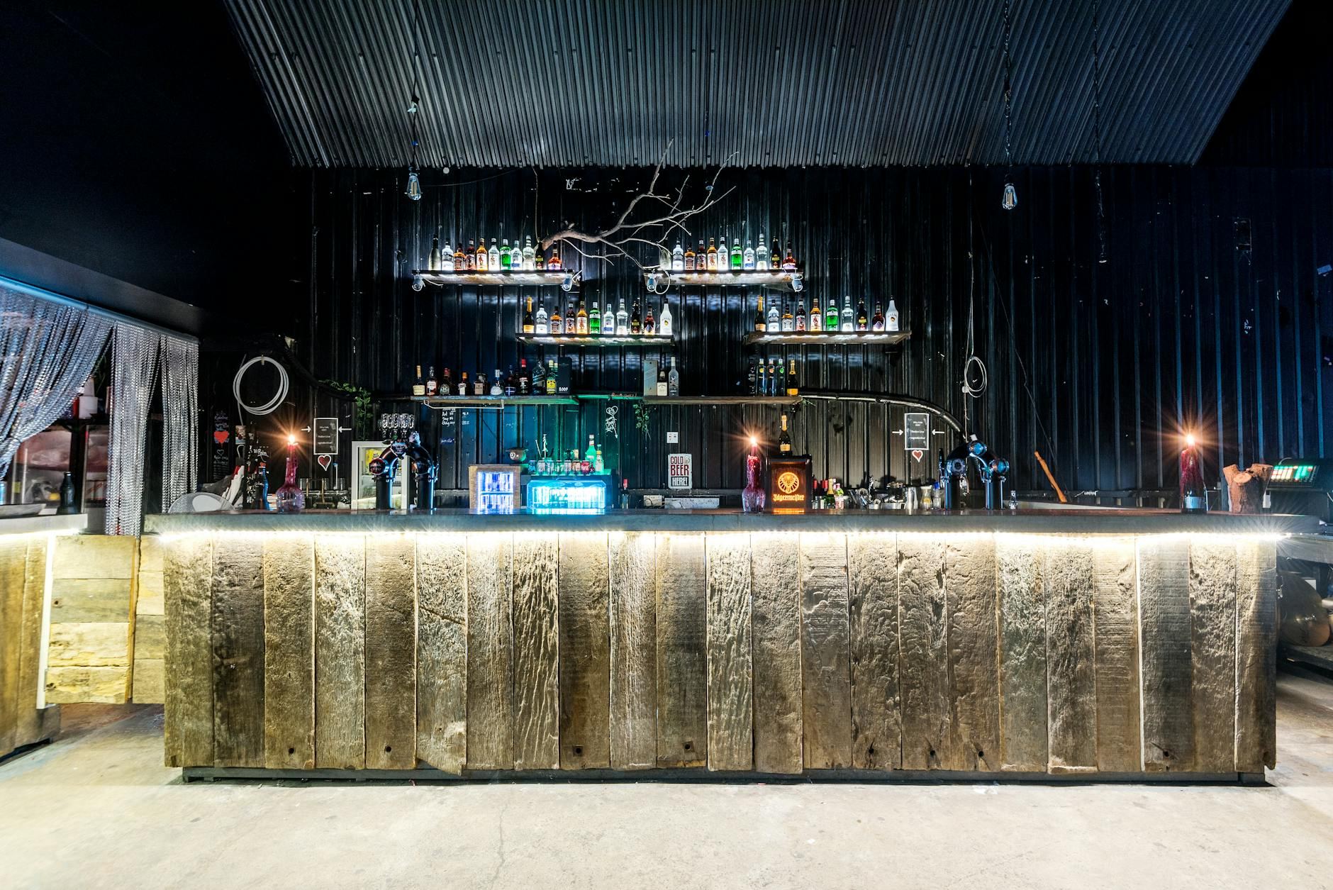 A stylish and modern bar interior featuring a rustic wooden counter and ambient lighting, creating a unique nightlife atmosphere.