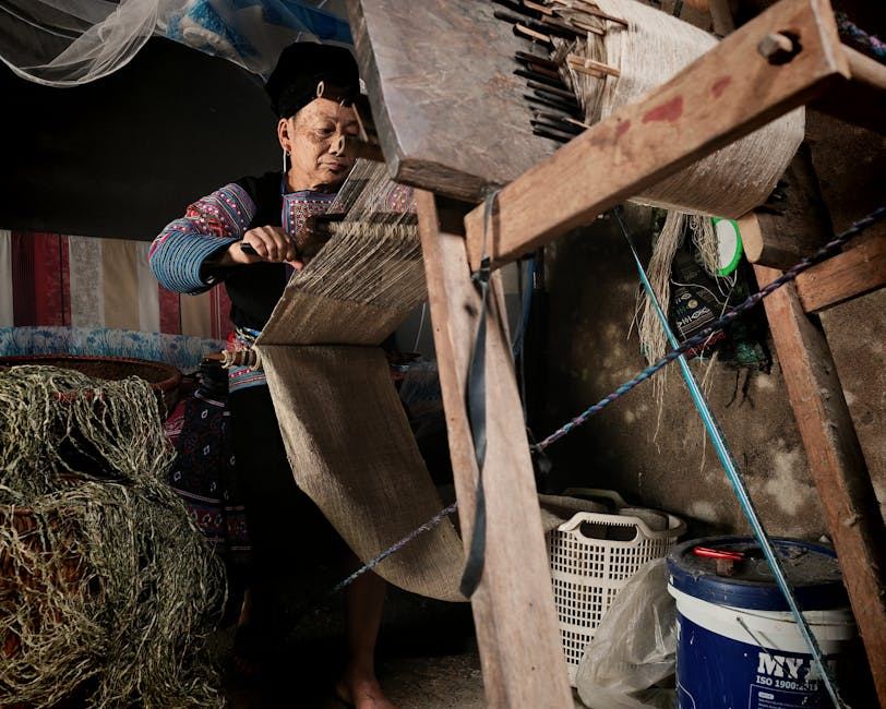 A person weaving textiles on a loom, showcasing traditional craftsmanship in a cozy indoor setting.