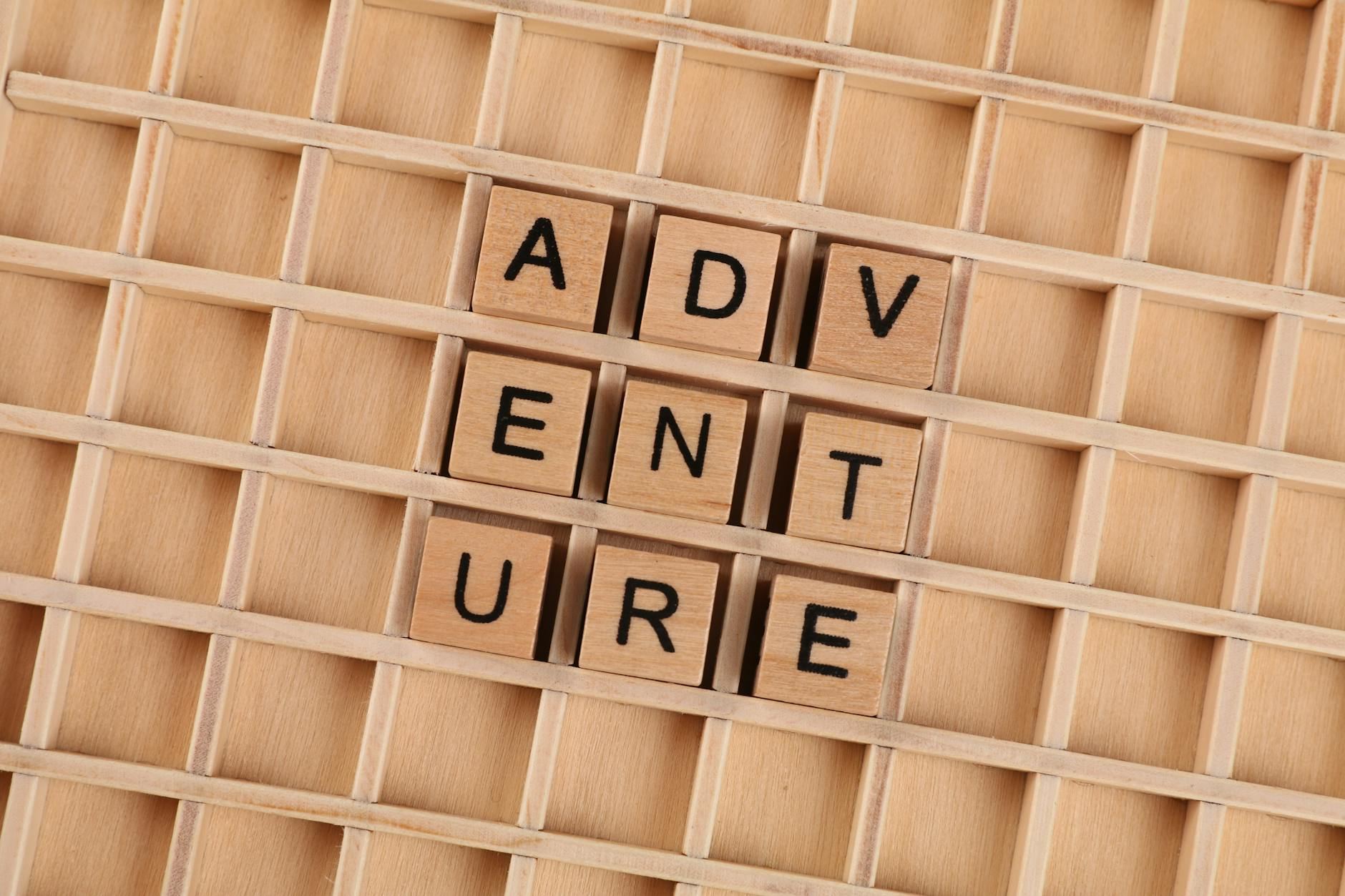 Colorful wooden blocks spell 'Adventure' on a textured grid, inviting participants to embark on a playful scavenger hunt.