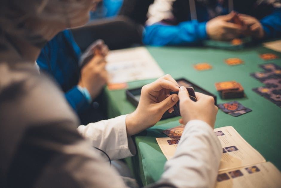 Players engaged in a strategic card game, focusing on their hands and Hearthstone cards on the table.