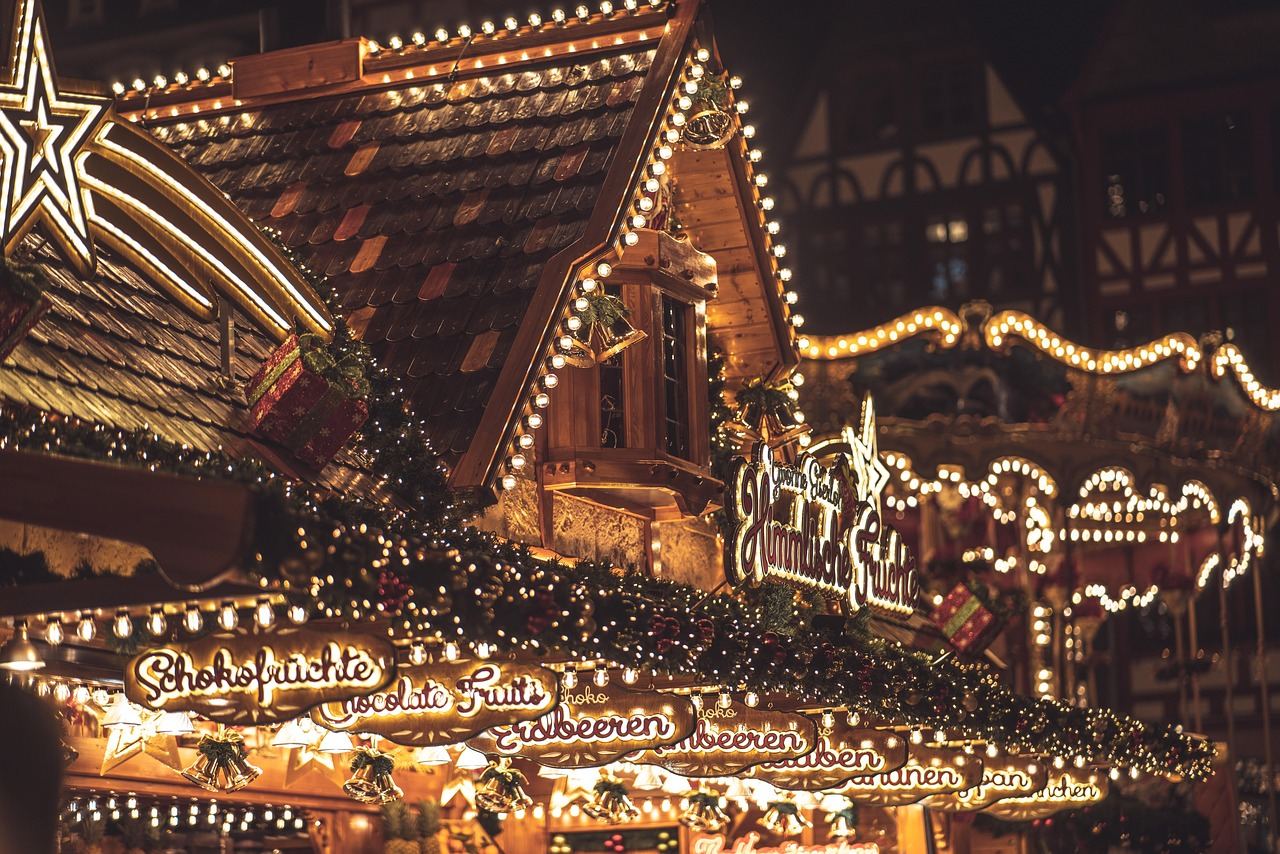 Twinkling fairy lights drape overhead, illuminating vibrant stalls filled with festive decorations and seasonal treats at the holiday market.