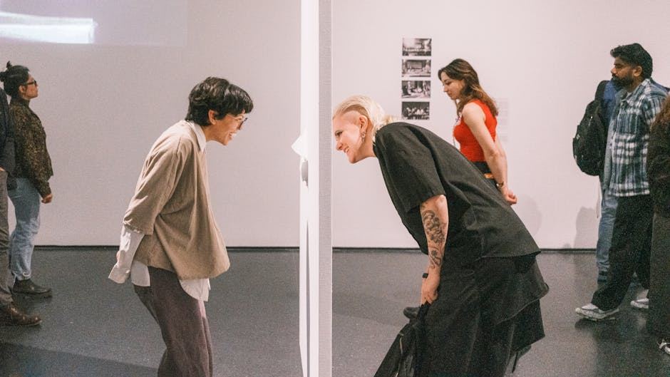 Two individuals engaging with an interactive art installation, surrounded by other visitors in an art gallery.