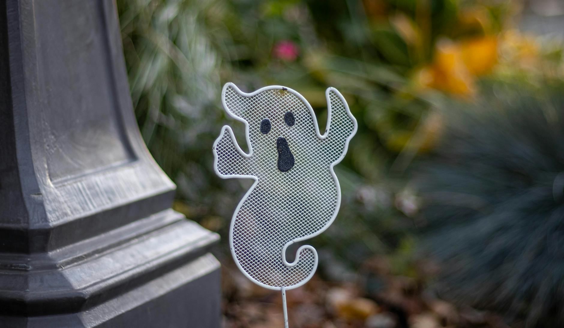 A spooky ghost decoration beside a garden post, perfect for Halloween themes.
