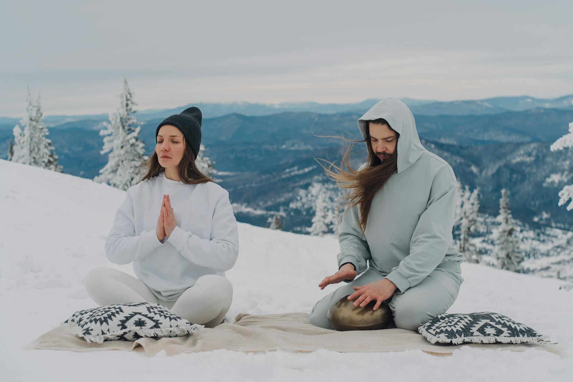 Couple meditating in serene snowy landscape, embracing mindfulness in winter scenery.