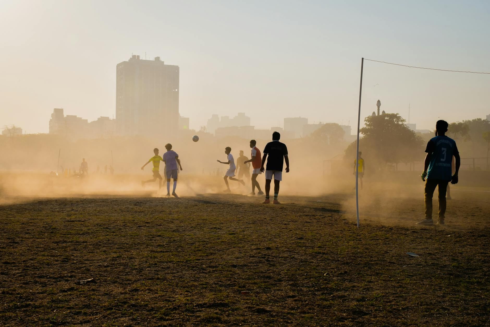 Vibrant scene of boys playing football on a dusty field in Kolkata, capturing youthful energy.