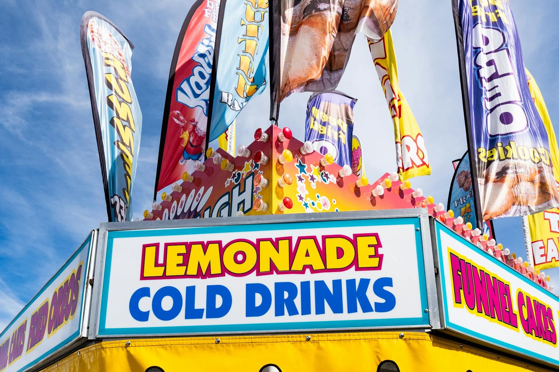 A colorful carnival stand brimming with refreshing lemonade and cold drinks, set against the lively backdrop of West Springfield.