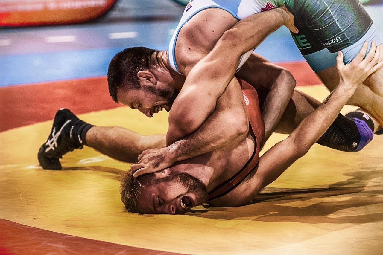 Two athletes engage in a fierce Lethwei match, showcasing powerful strikes and dynamic grappling techniques in a vibrant arena.