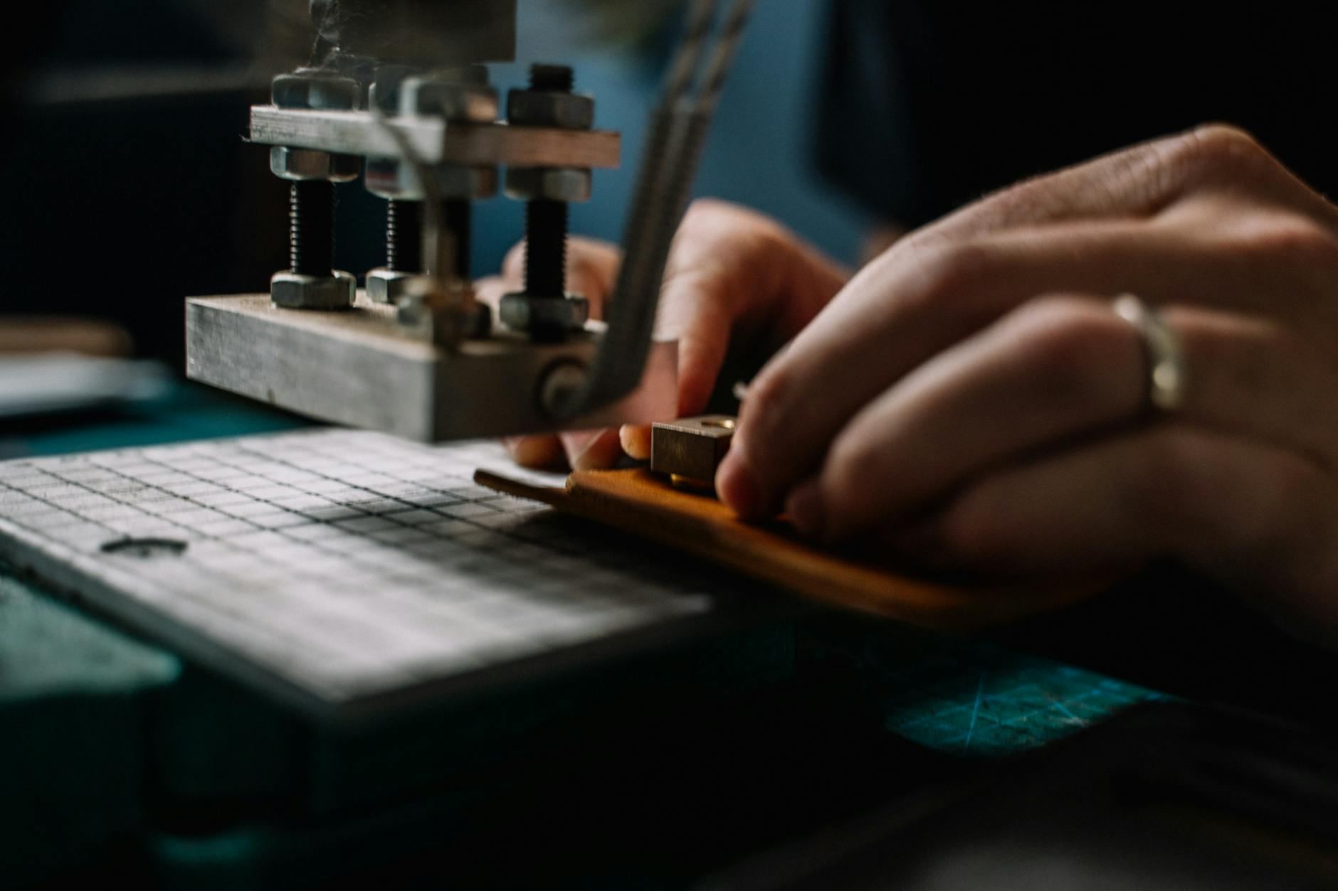 Close-up of a leather artisan using metal tools to craft leather goods in a creative workspace.