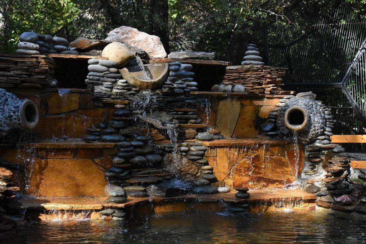 A serene fountain surrounded by lush greenery and colorful flowers, inviting visitors to relax in the zoo.
