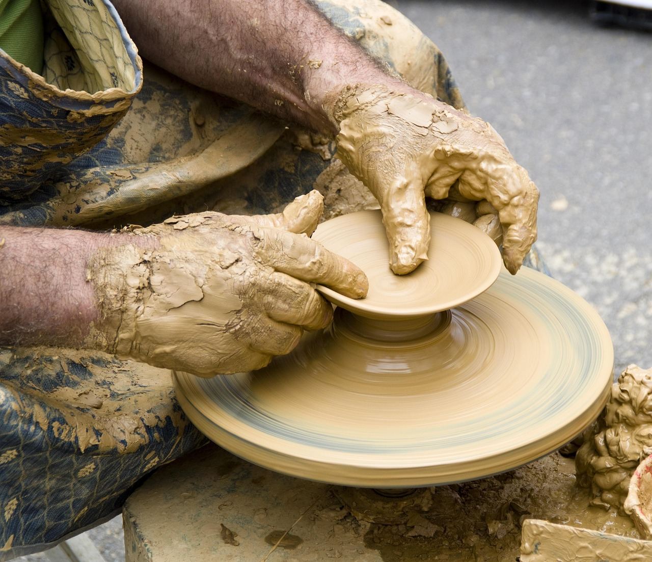 A skilled potter shapes a wet clay bowl on a spinning wheel, showcasing the art of wheel throwing.