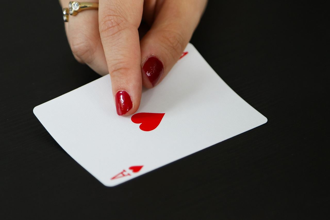 A close-up view of a shiny ace of hearts playing card, showcasing its vibrant red color and intricate design.