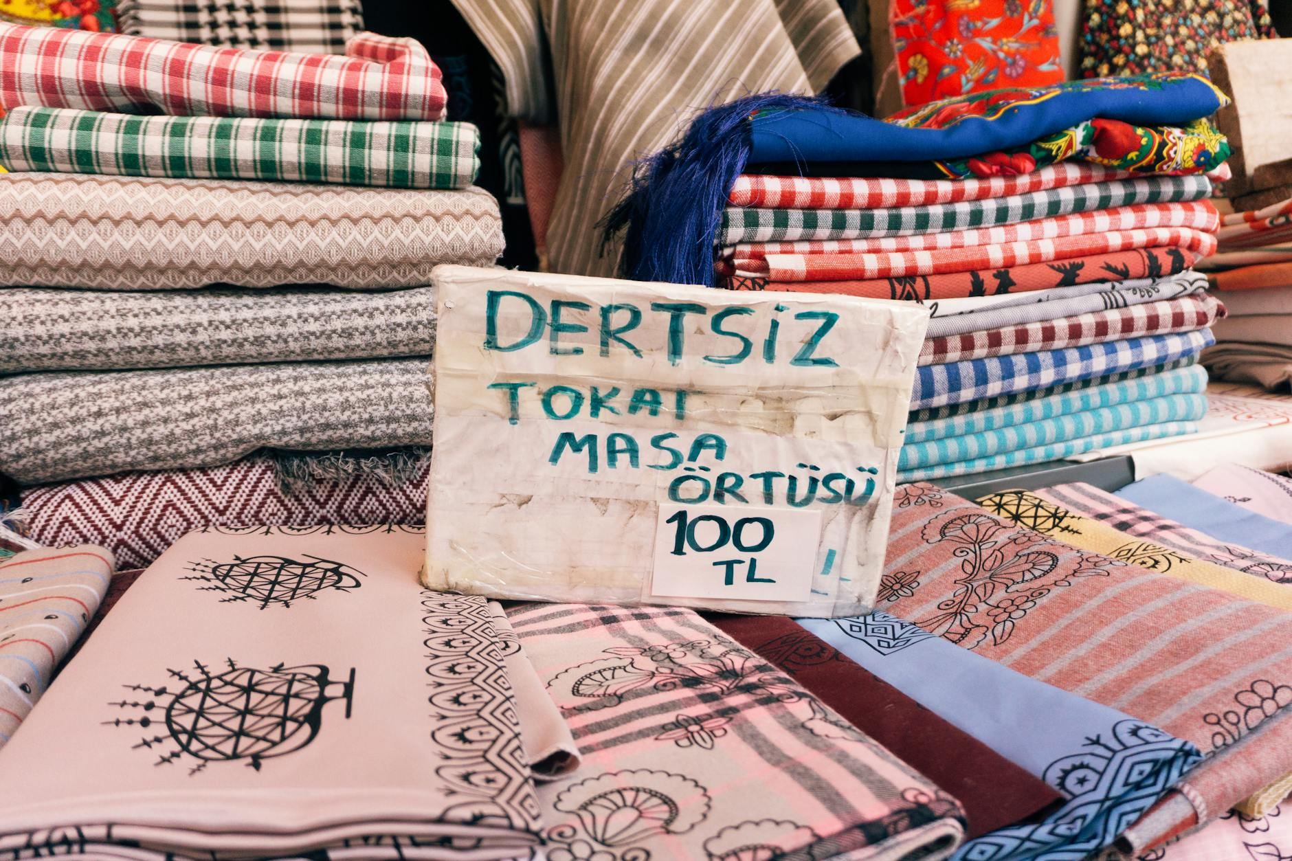 Colorful Turkish textiles in various patterns and hues are beautifully arranged on display at a bustling market stall.