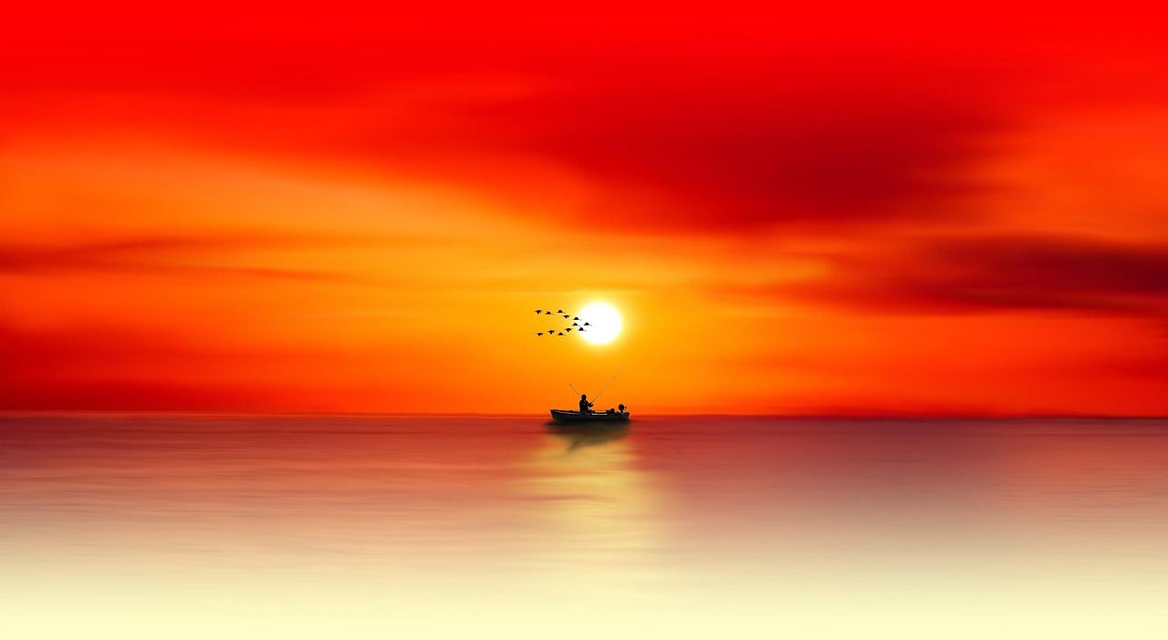 A vibrant sunset casts warm hues over calm waters, creating a serene backdrop for saltwater fishing enthusiasts.