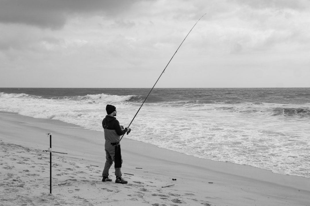 Man fishing on a sandy beach with waves crashing