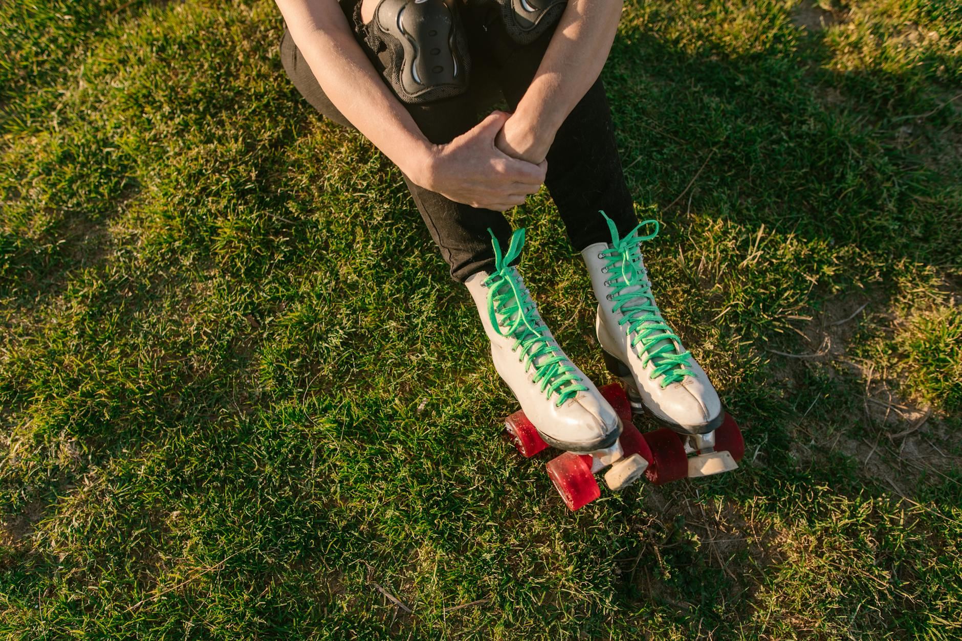 A person in colorful roller skates relaxes on the grass, basking in the sun during a leisurely outdoor break.