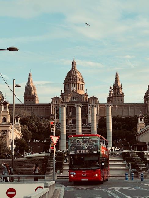 A red double-decker bus in front of a grand architectural building, ideal for bus spotting enthusiasts.