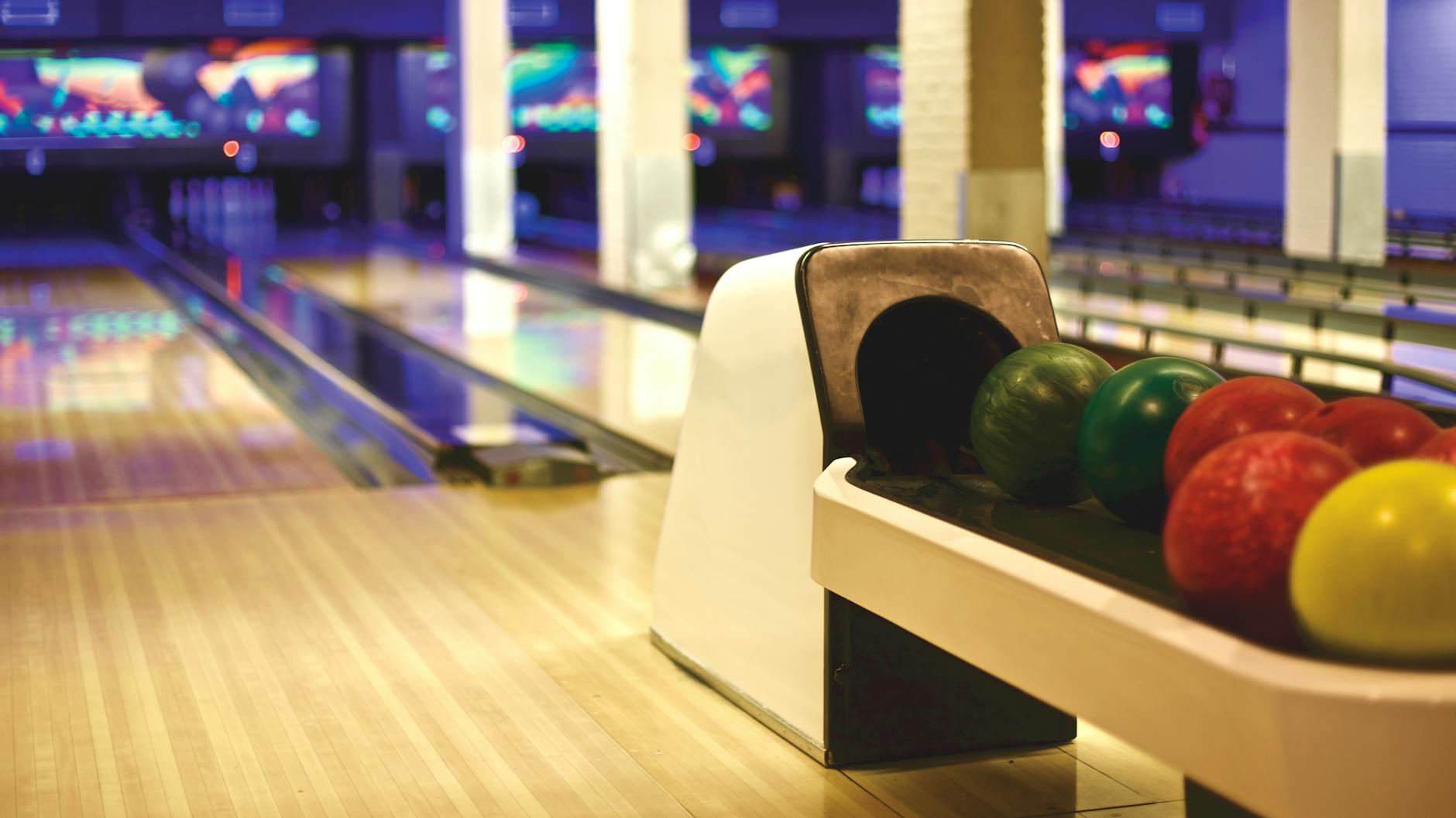 Colorful bowling balls lined up in a modern alley, ready for a thrilling game night.