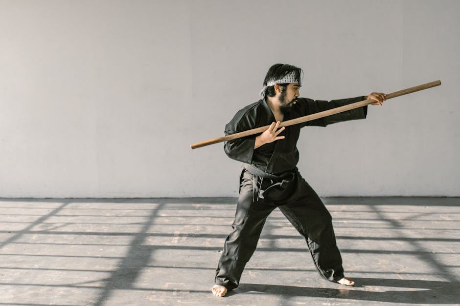 A martial artist practices with a wooden staff, showcasing techniques relevant to the Marine Corps Martial Arts Program.