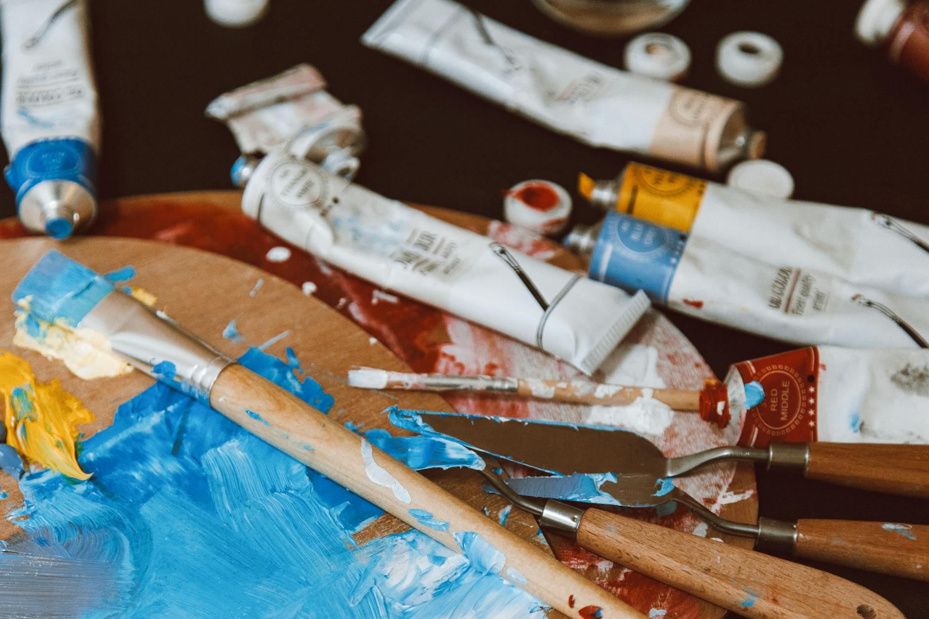 A vibrant artist's palette filled with colorful paints, surrounded by paintbrushes and tubes, ready for creative expression.