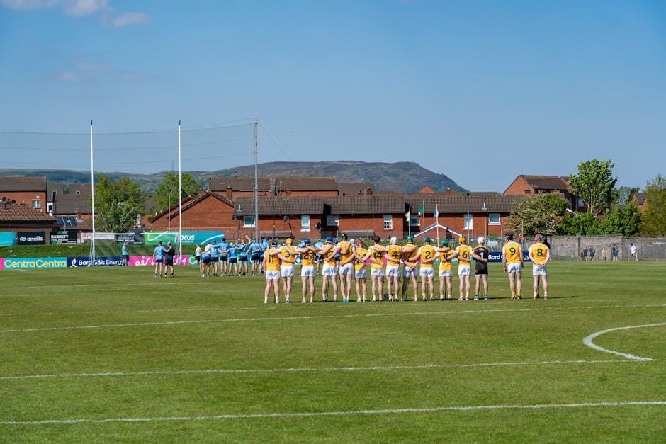Players lined up on a field, preparing for a Gaelic Football match under a clear blue sky.