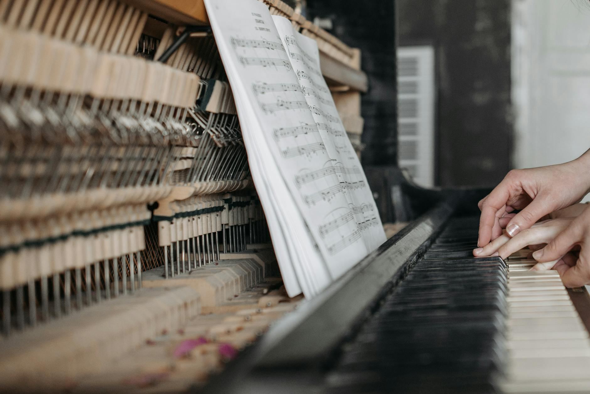 Hands gracefully pressing piano keys, surrounded by open sheet music, highlighting the essence of music theory education.