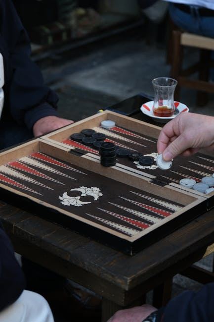 Two players engaged in a game of backgammon with pieces on a wooden board.