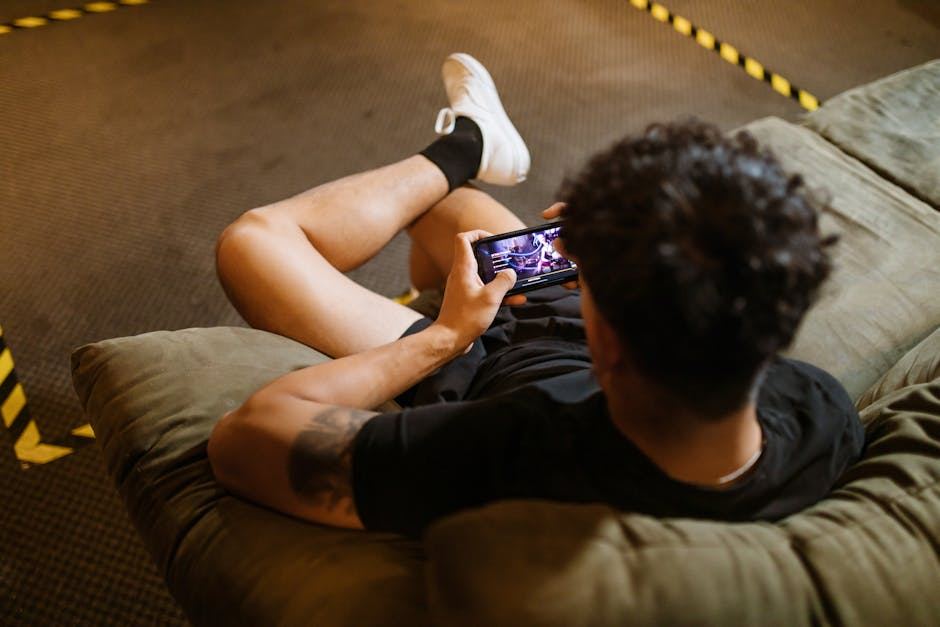 A person sitting on a couch, playing a mobile game on their smartphone.