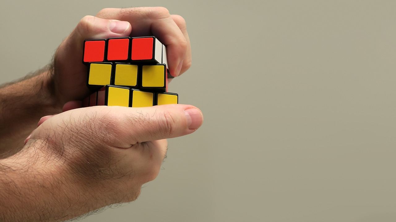 A hand skillfully manipulating a colorful Rubik's Cube, showcasing a mix of vibrant colors and intricate patterns.