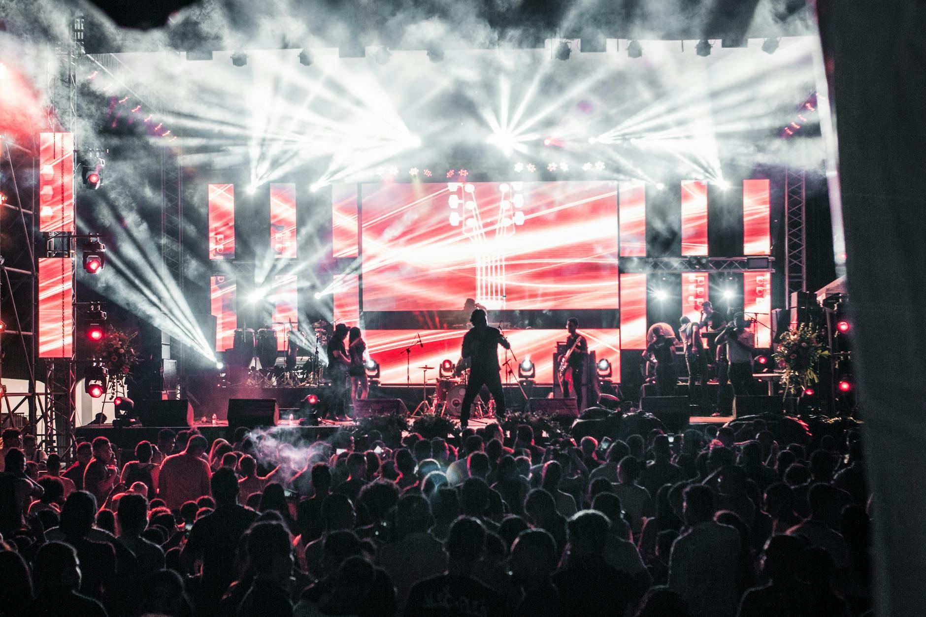 A lively outdoor concert scene with dynamic performers on stage, energizing a captivated crowd under colorful lights.