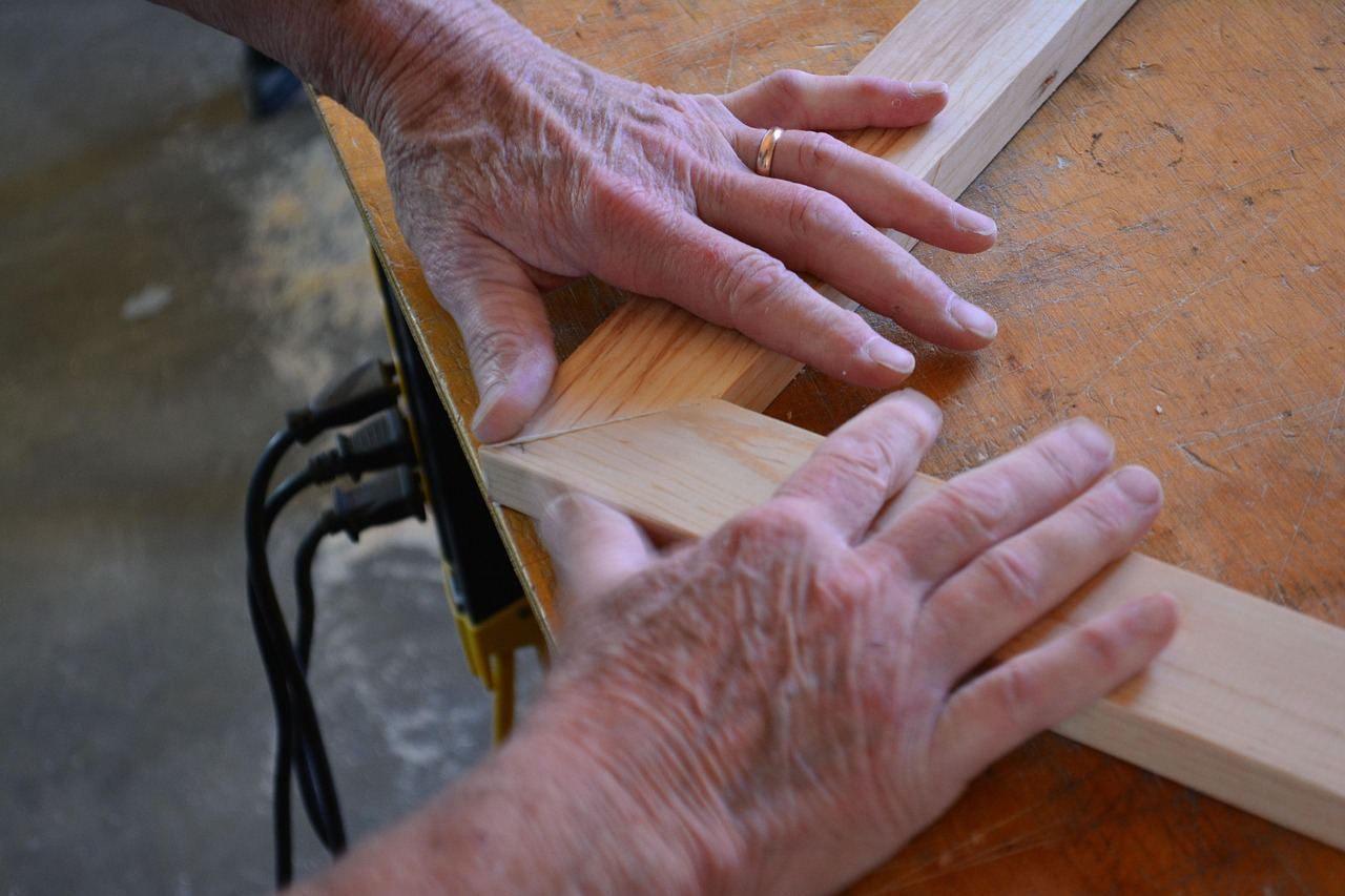 A skilled woodworker carefully shaping a wooden piece with a chisel, surrounded by tools and wood shavings.