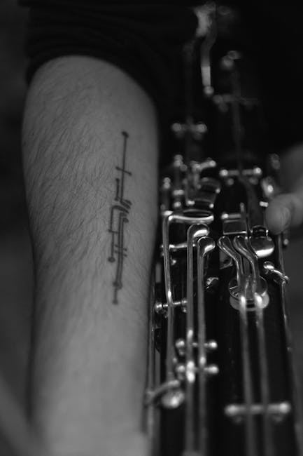 A close-up of a person's arm with a clarinet tattoo, holding a clarinet.