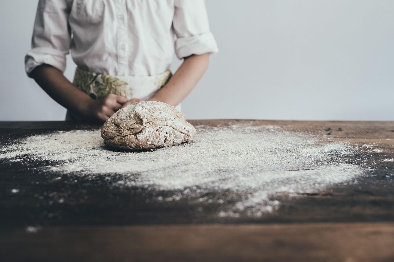 A person kneading dough on a wooden table, exploring if bread making is for you. Let's find out!