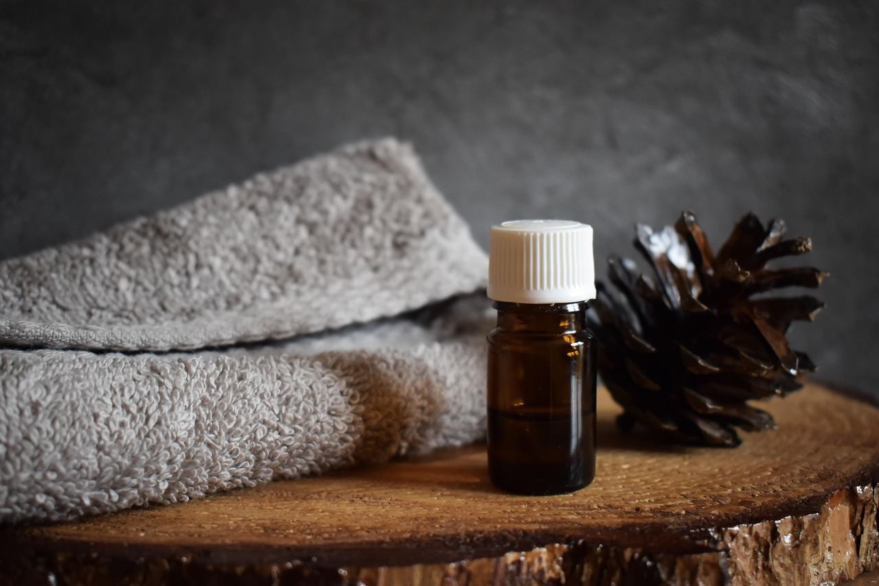 Essential oils and a pine cone on a wooden surface, exploring fragrance creation in 'Is Perfume Making for you?'.