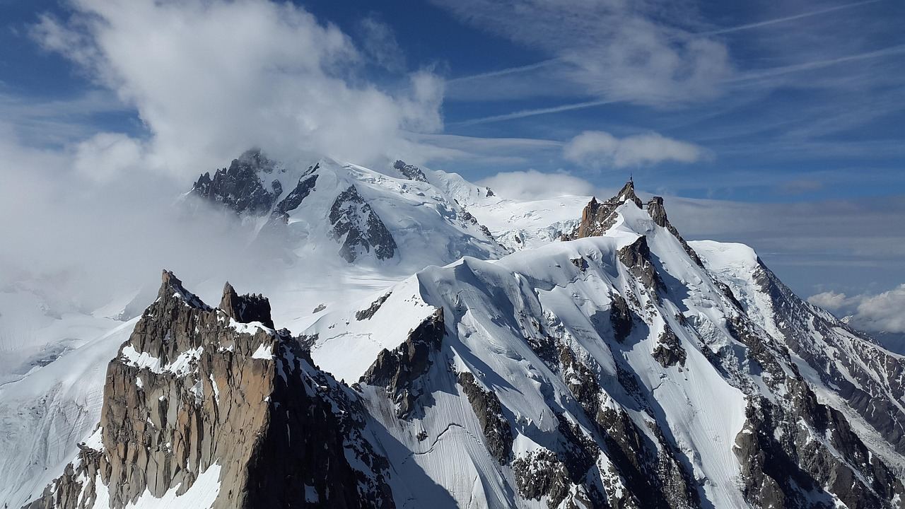 Majestic snow-capped peaks rise against a clear blue sky, inviting adventurers to explore their rugged terrain.