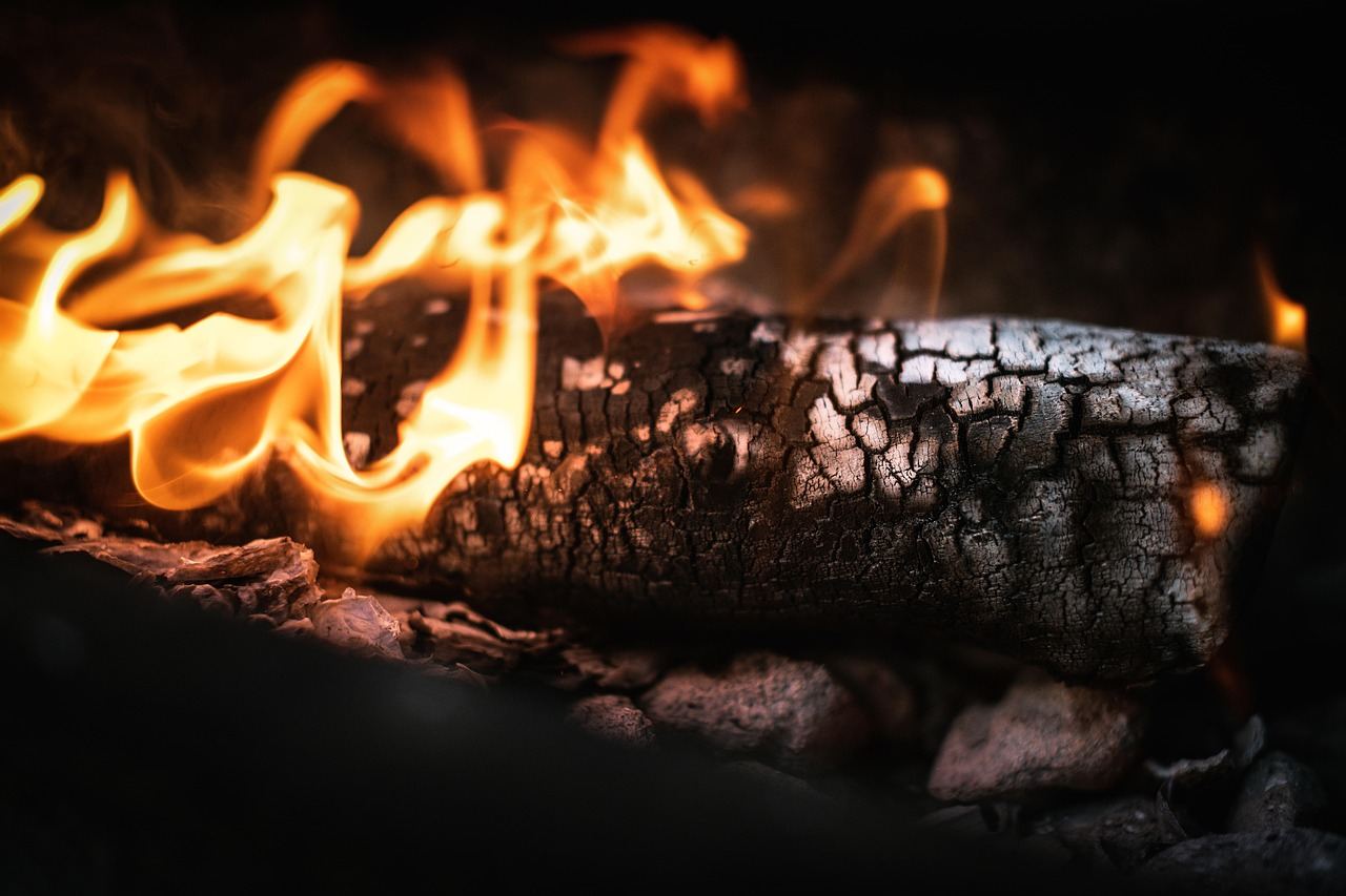 A flickering flame dances atop a wooden surface, casting warm light and shadows that hint at creative possibilities.