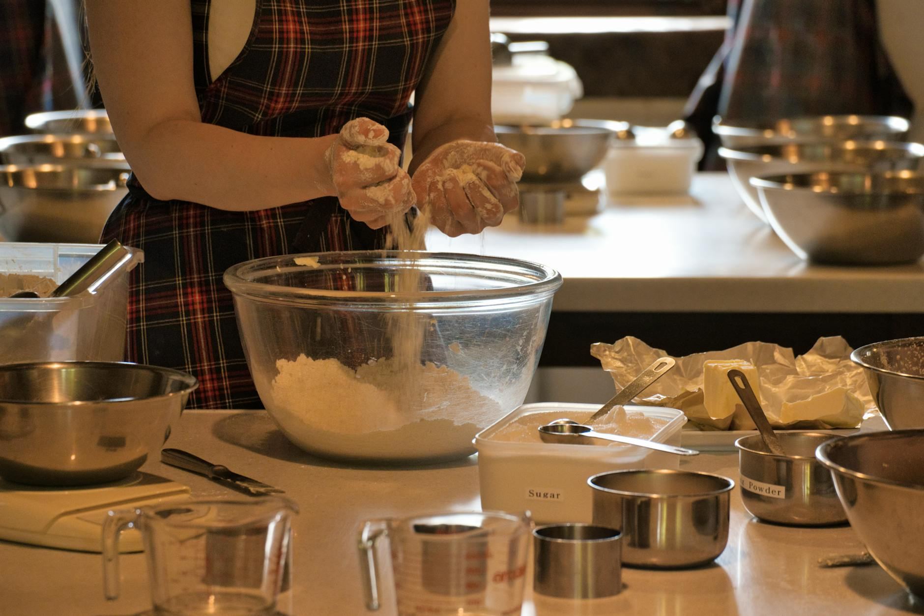 A woman vigorously mixes ingredients in a bowl surrounded by colorful kitchenware during an engaging baking class.