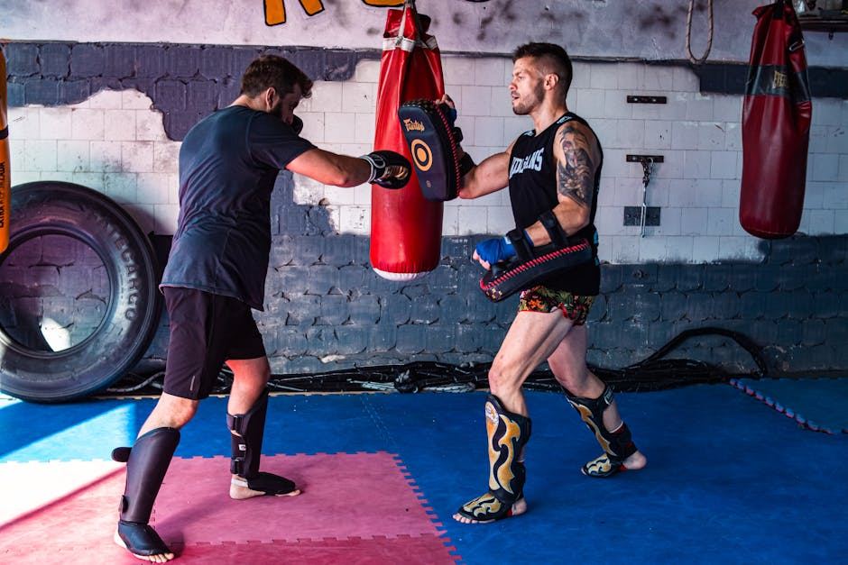 Two kickboxers sparring in a gym, showcasing techniques with gloves and shin guards.