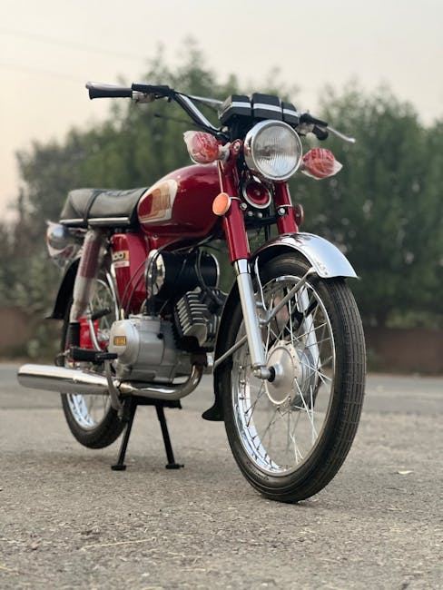 A classic red motorcycle parked on a road, showcasing its restored vintage design.